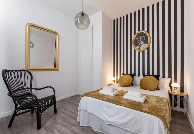 Dormitorio principal con pared de rayas en el apartamento Queen's Chueca III, Madrid
