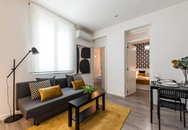 Salón con sofá gris y alfombra amarilla en el apartamento Queen's Chueca III, Madrid