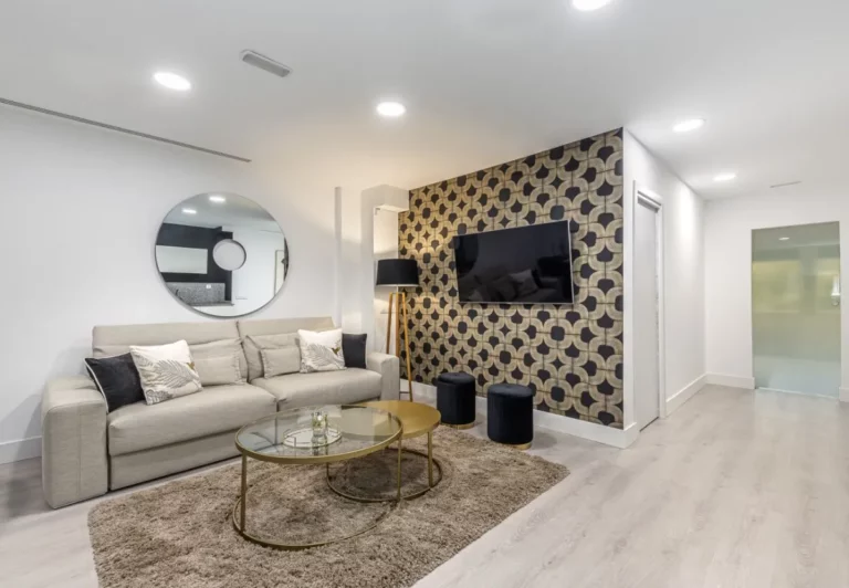 Salón con sofá crema y mesas doradas en el apartamento Queen's Retiro I, Madrid