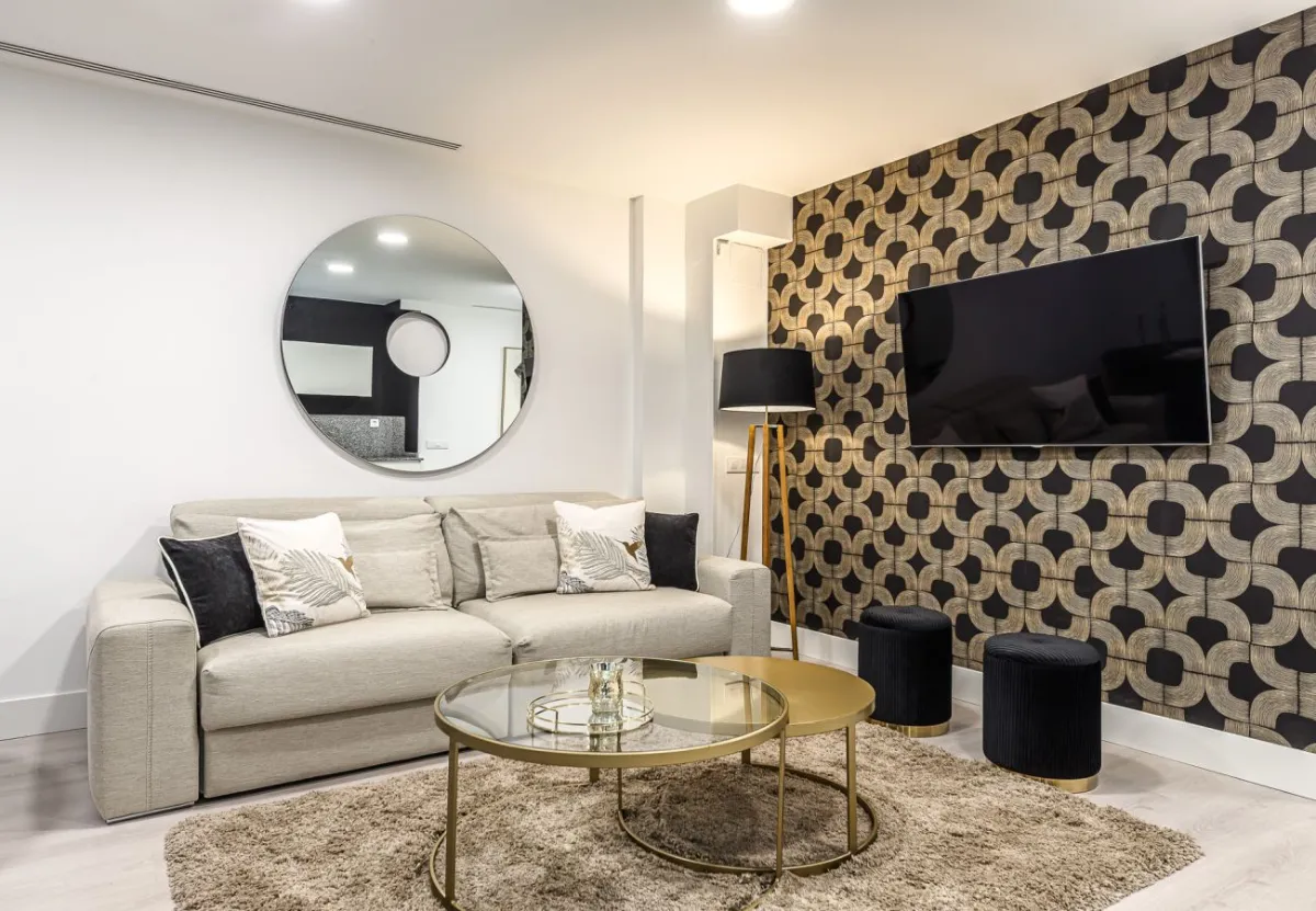 Salón con papel geométrico negro y dorado en el apartamento Queen's Retiro I, Madrid
