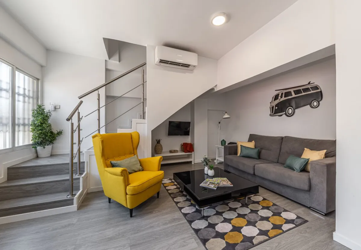 Salón con escalera y butaca mostaza en el apartamento Queen's Retiro III, Madrid