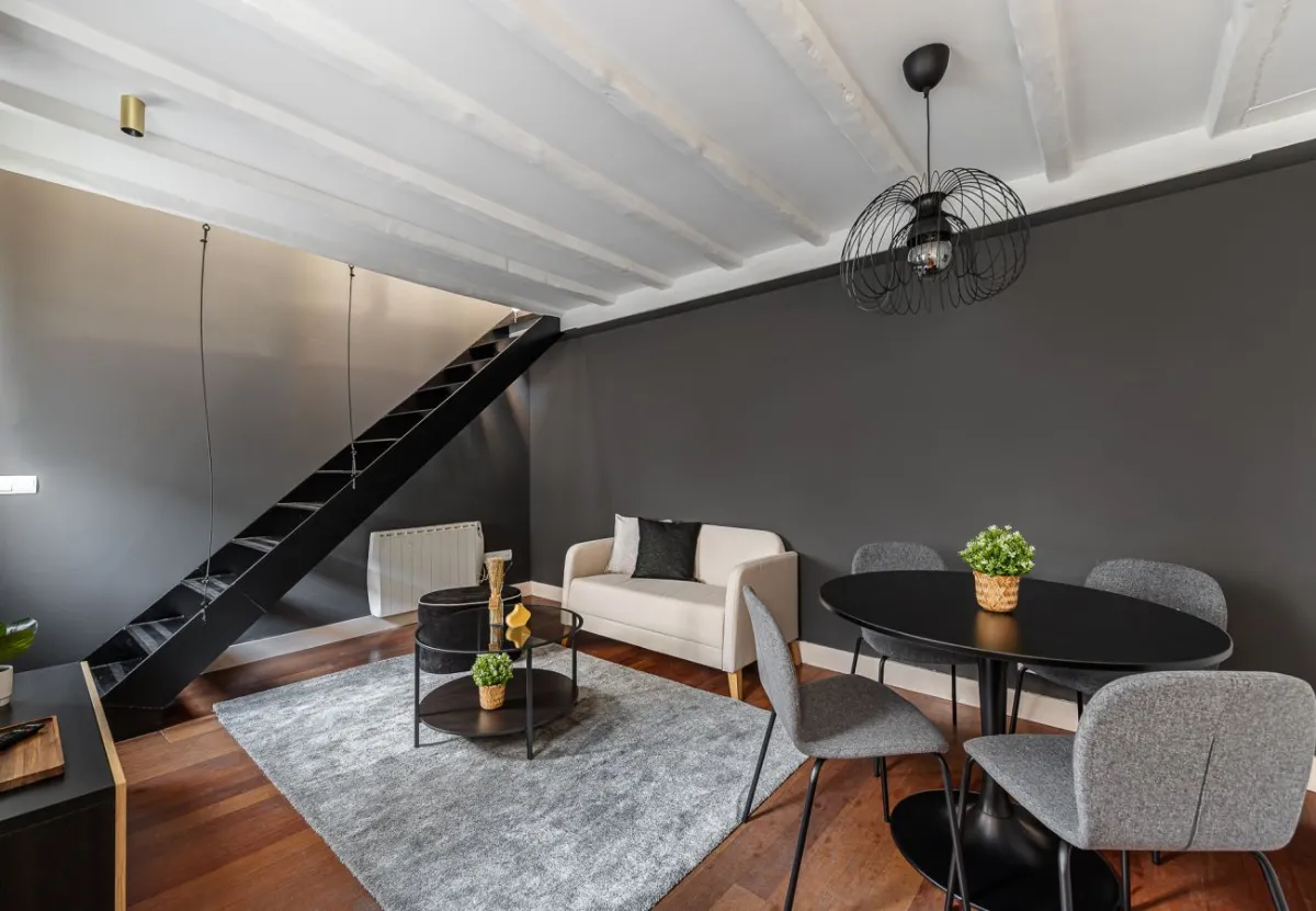 Salón con vigas y escalera de hierro en el apartamento Queen's Las Letras II, Madrid