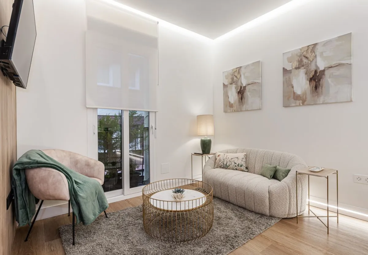 Salón con sofá curvo y butaca rosa en el apartamento Queen's Retiro IV, Madrid