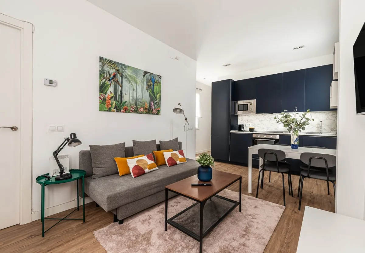 Salón con sofá y cocina al fondo en el apartamento Queen's Atocha I, Madrid