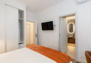 Armario, televisión y puerta del baño en la habitación Queen's Bernabéu I, coliving en Chamartín, Madrid
