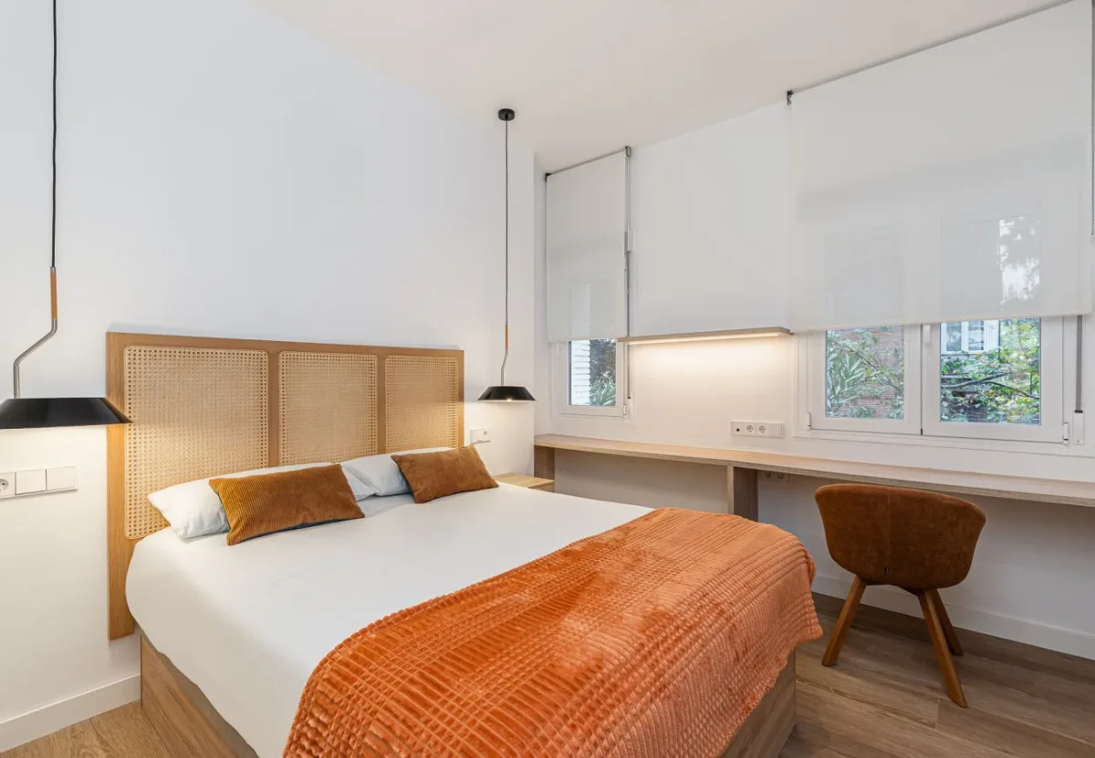 Dormitorio con escritorio bajo la ventana en la habitación Queen's Bernabéu II, coliving en Chamartín, Madrid