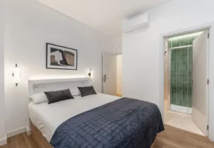 Cama de matrimonio con apliques de pared en la habitación Queen's Bernabéu III, coliving en Chamartín, Madrid