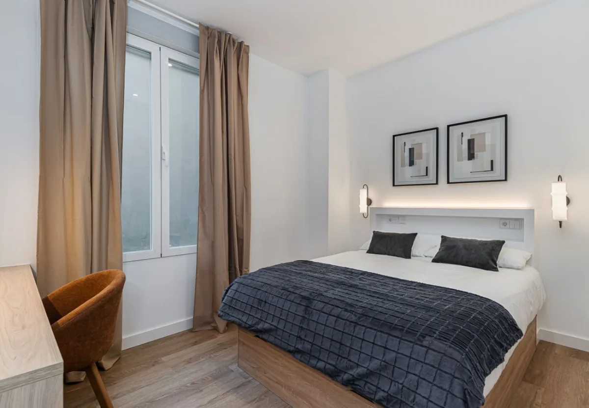 Dormitorio con colcha azul marino y dos cuadros en la habitación Queen's Bernabéu IV, coliving en Chamartín, Madrid