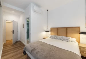 Cama de matrimonio con lámparas colgantes en la habitación Queen's Bernabéu VI, coliving en Chamartín, Madrid