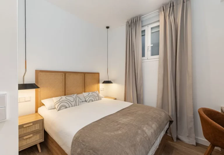 Dormitorio con cabecero de rejilla y colcha gris en la habitación Queen's Bernabéu VI, coliving en Chamartín, Madrid