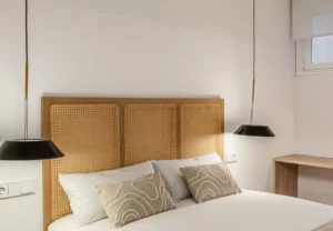Cabecero de rejilla con cojines estampados en la habitación Queen's Bernabéu VII, coliving en Chamartín, Madrid
