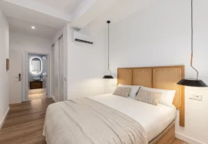 Cama de matrimonio con colcha beige en la habitación Queen's Bernabéu VII, coliving en Chamartín, Madrid
