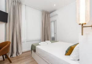 Cama de matrimonio y cortinas en la habitación Queen's Bernabéu VIII, coliving en Chamartín, Madrid