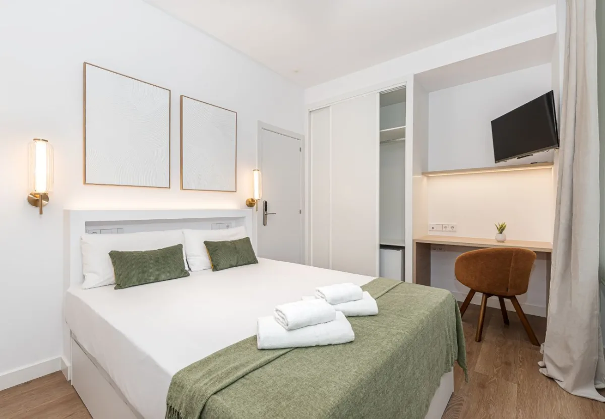 Dormitorio con colcha verde y escritorio en la habitación Queen's Bernabéu VIII, coliving en Chamartín, Madrid