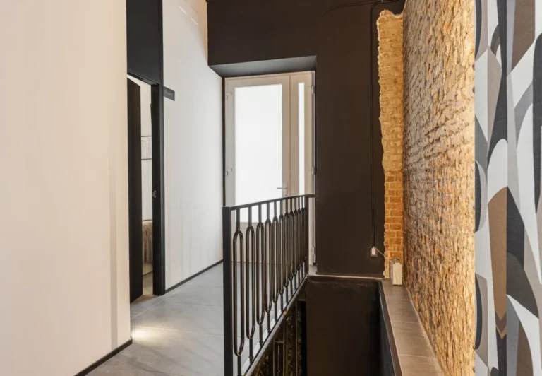 Rellano con barandilla y pared de ladrillo en The Queen's Coliving Chamberí, Ríos Rosas, Madrid