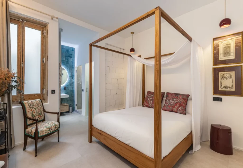 Cama con dosel de madera y visillos en la habitación Queen's House Chueca I, hotel boutique en Chueca, Madrid