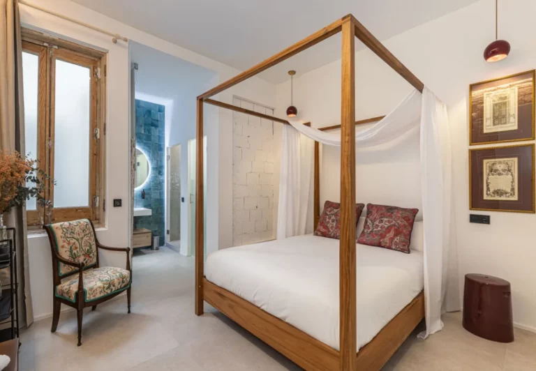 Cama con dosel de madera y visillos en la habitación Queen's House Chueca I, hotel boutique en Chueca, Madrid