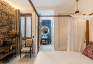 Dormitorio con ladrillo visto y baño al fondo en la habitación Queen's House Chueca I, hotel boutique en Chueca, Madrid