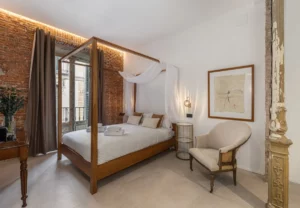 Dormitorio con dosel y ladrillo visto en la habitación Queen's House Chueca II, hotel boutique en Chueca, Madrid