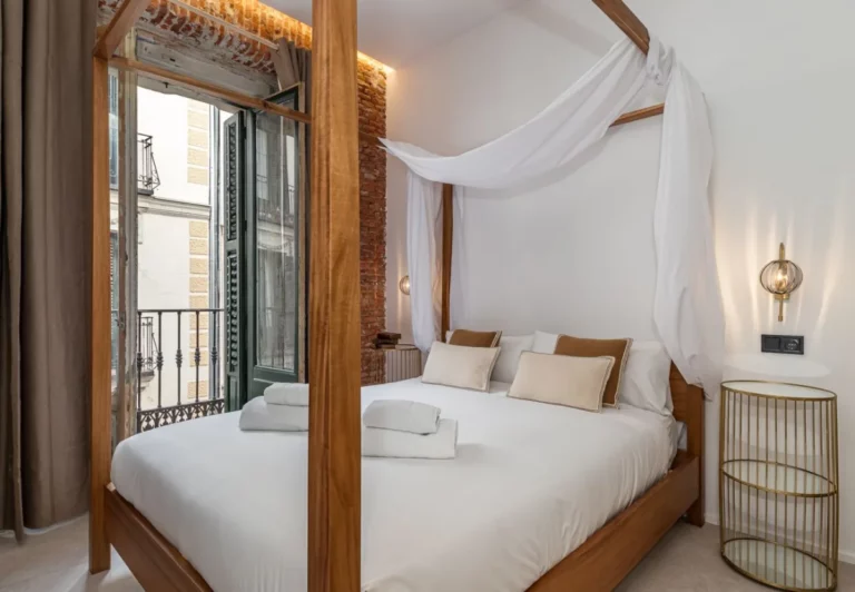 Cama con dosel junto al balcón en la habitación Queen's House Chueca II, hotel boutique en Chueca, Madrid