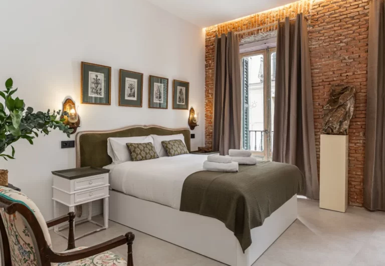 Dormitorio con cabecero verde oliva y grabados botánicos en la habitación Queen's House Chueca III, hotel boutique en Chueca, Madrid