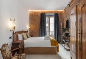 Dormitorio con ladrillo visto y armario antiguo en la habitación Queen's House Chueca IV, hotel boutique en Chueca, Madrid