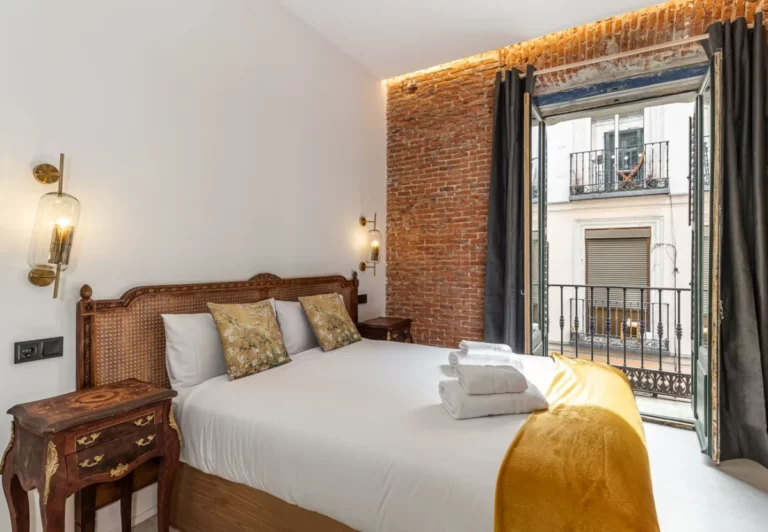 Cama con balcón a la calle en la habitación Queen's House Chueca IV, hotel boutique en Chueca, Madrid