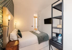 Cabecero de lino y estantería metálica en la habitación Queen's House Chueca VI, hotel boutique en Chueca, Madrid