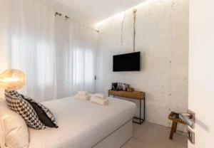 Cama con cojines blanco y negro en la habitación Queen's House Chueca VII, hotel boutique en Chueca, Madrid