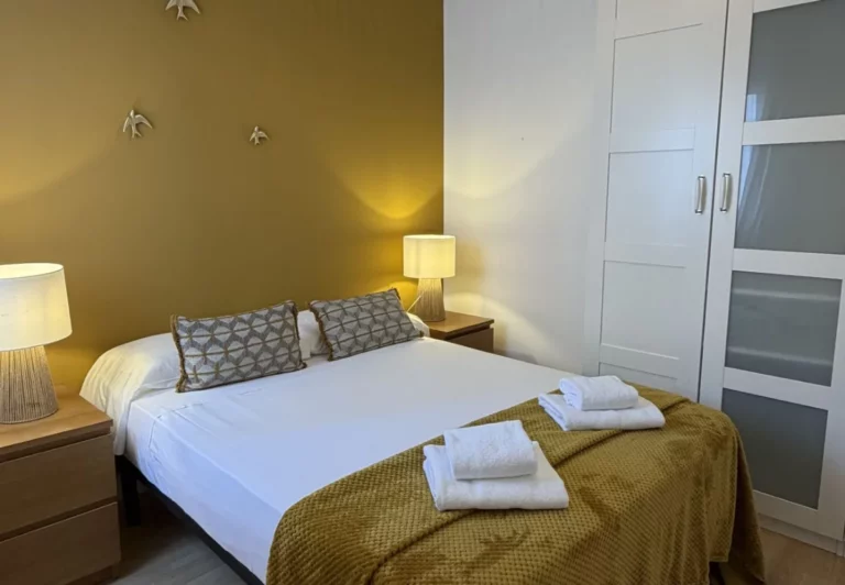 Dormitorio con pared mostaza en el apartamento Queen's Nuevos Ministerios I, Madrid