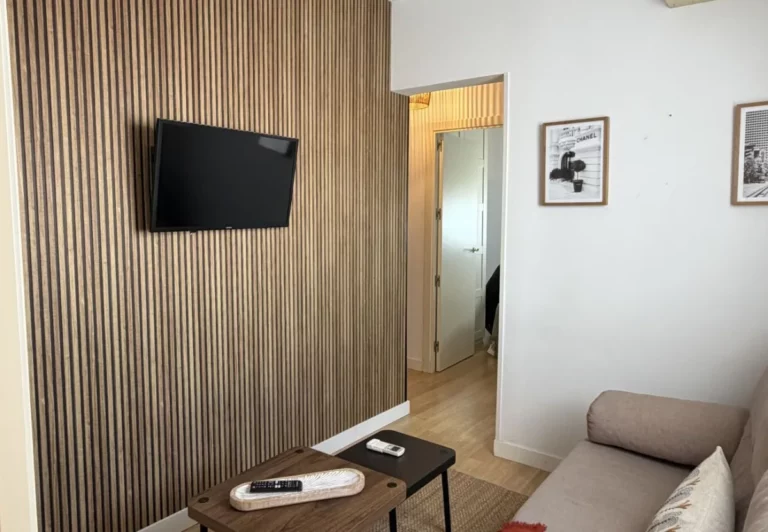 Salón con pared de listones de madera en el apartamento Queen's Nuevos Ministerios I, Madrid
