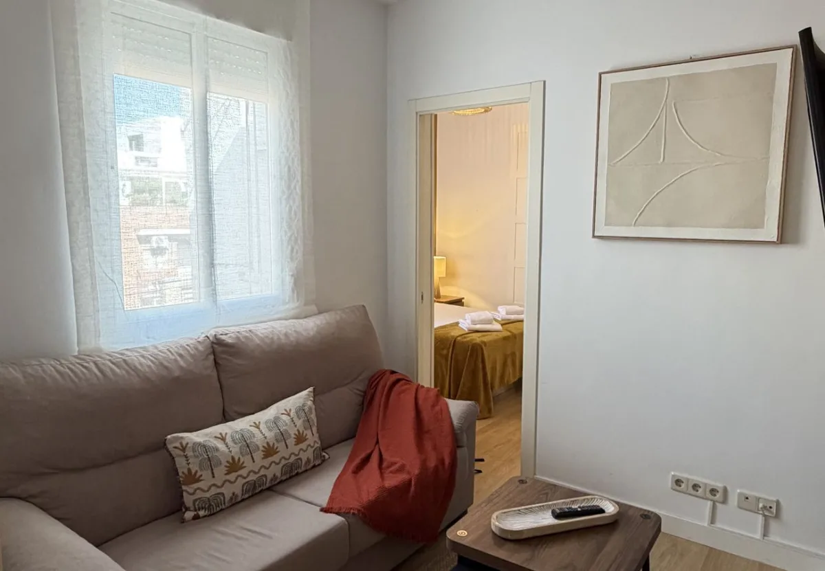 Salón con sofá y ventana en el apartamento Queen's Nuevos Ministerios I, Madrid