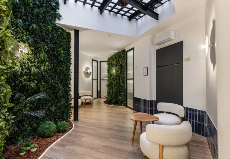 Pasillo y zona de estar con plantas en el coliving The Queen's Olavide, Chamberí, Madrid