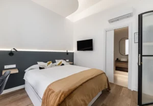Cama de matrimonio y puerta de cristal en la habitación Queen's Olavide I, coliving en Chamberí, Madrid