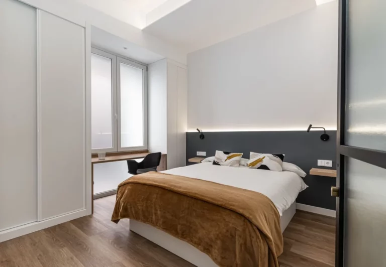 Dormitorio con colcha camel y escritorio en la habitación Queen's Olavide I, coliving en Chamberí, Madrid