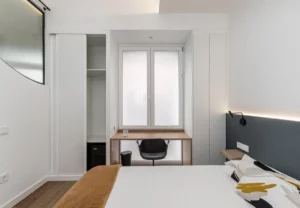 Escritorio junto a la ventana y armario en la habitación Queen's Olavide I, coliving en Chamberí, Madrid