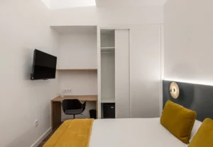 Escritorio, armario y televisión en la habitación Queen's Olavide III, coliving en Chamberí, Madrid