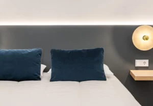 Cama de matrimonio con cojines azul petróleo en la habitación Queen's Olavide IV, coliving en Chamberí, Madrid