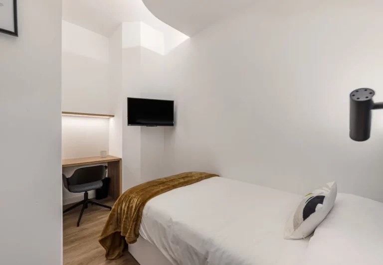 Dormitorio individual con escritorio y televisión en la habitación Queen's Olavide V, coliving en Chamberí, Madrid