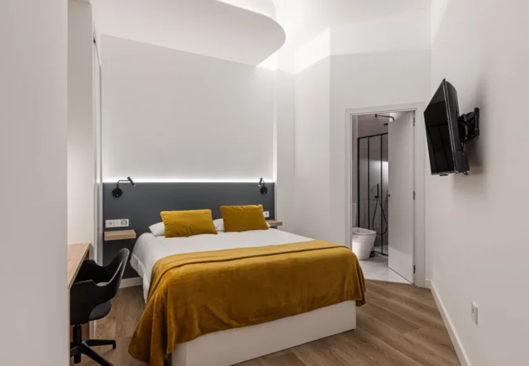 Dormitorio con colcha mostaza y escritorio en la habitación Queen's Olavide VI, coliving en Chamberí, Madrid
