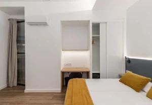 Escritorio bajo la ventana y armario en la habitación Queen's Olavide VI, coliving en Chamberí, Madrid