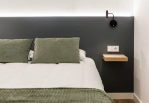 Cabecero gris con cojines verdes en la habitación Queen's Olavide VII, coliving en Chamberí, Madrid