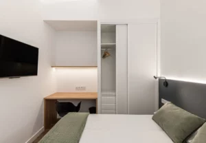 Escritorio y armario con baldas en la habitación Queen's Olavide VII, coliving en Chamberí, Madrid