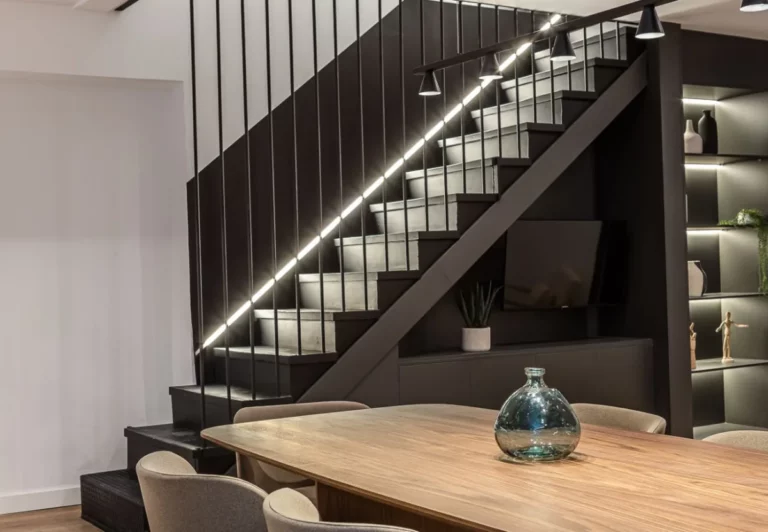 Escalera iluminada y comedor compartido en el coliving The Queen's Plaza España, Argüelles, Madrid