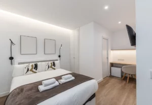 Cama y escritorio al fondo, Queen's Plaza España II, coliving en Argüelles, Madrid