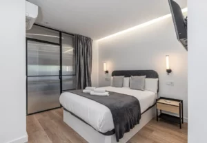 Dormitorio con puerta de cristal y acero, Queen's Plaza España III, coliving en Argüelles, Madrid