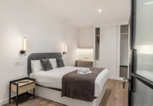 Cama con cojines de pelo y apliques, Queen's Plaza España IV, coliving en Argüelles, Madrid