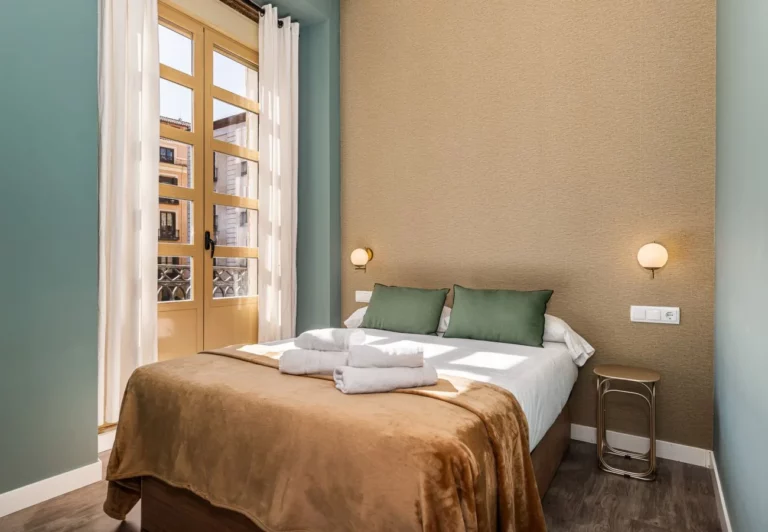 Dormitorio con cama de matrimonio y ventanal en el apartamento de Puerta del Sol