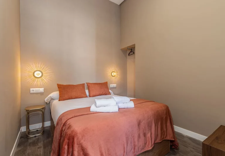 Segundo dormitorio con cama de matrimonio y apliques dorados