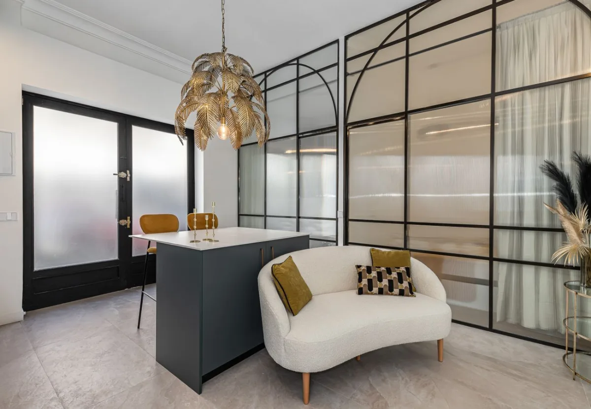 Salón con sofá curvo y cocina con isla en el apartamento Queen's Salamanca II, Madrid